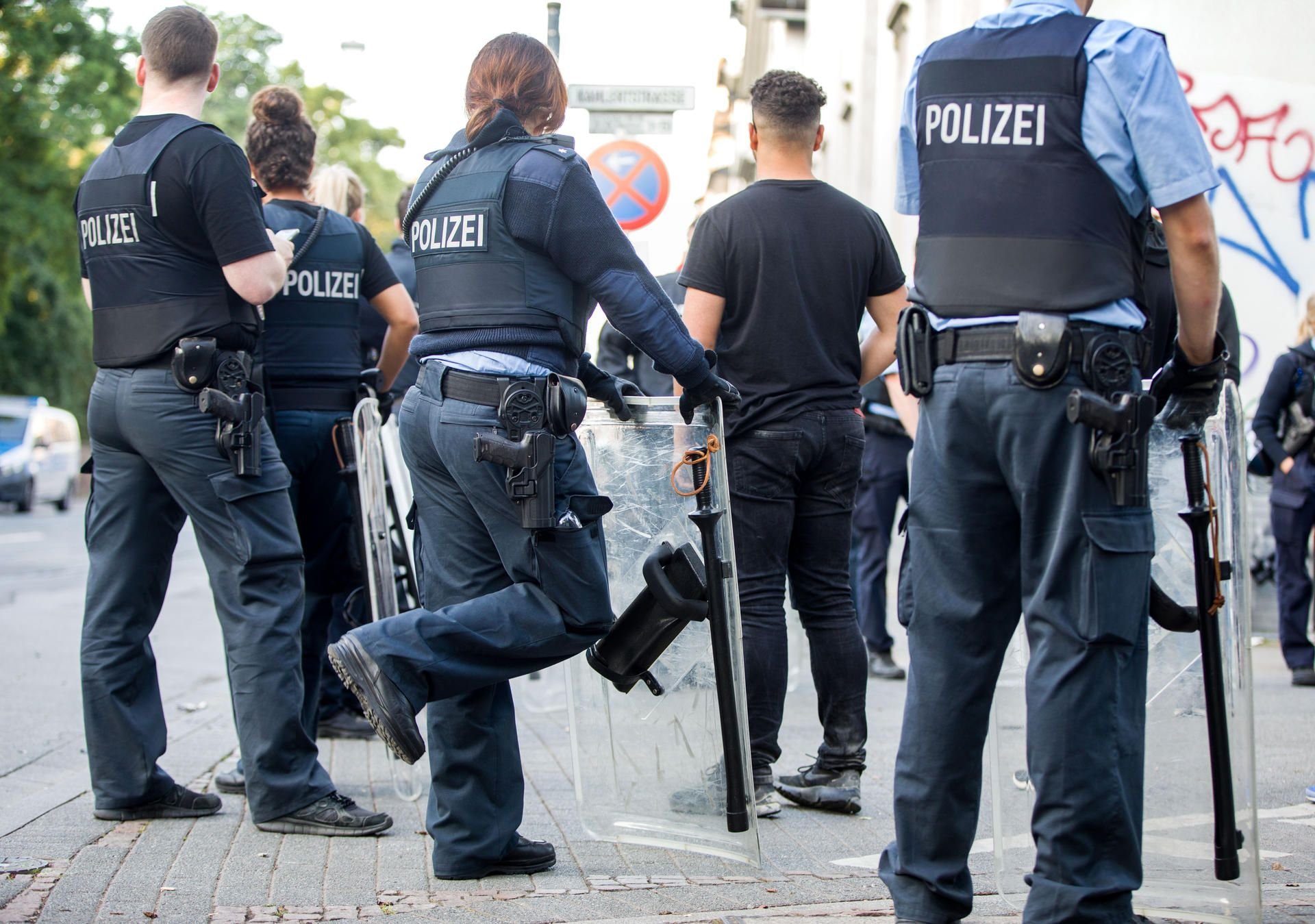 Gewalt nach Musikfestival in Darmstadt: Polizisten bewachen am frühen Morgen eine Gruppe festgesetzter junger Männer neben dem Herrngarten am Rande der Innenstadt.