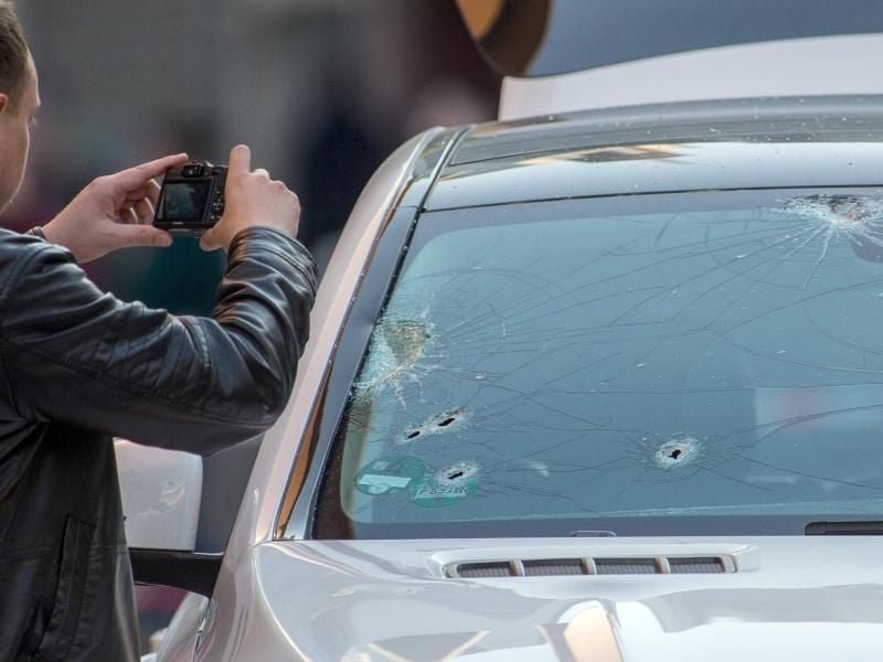 Mitarbeiter der Spurensicherung fotografiert Einschusslöcher in Fahrzeug. Foto: A.Arnold/Archiv