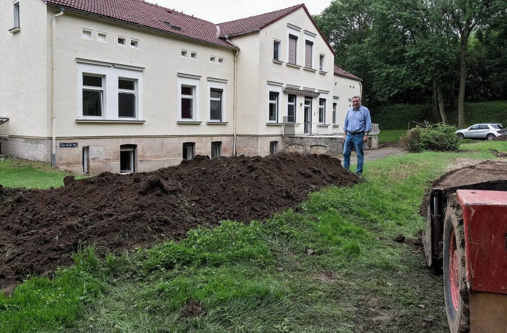 Wolfgang Hick steht in Schraplau vor einem Erdwall, der sein Haus künftig vor Fluten schützen soll.