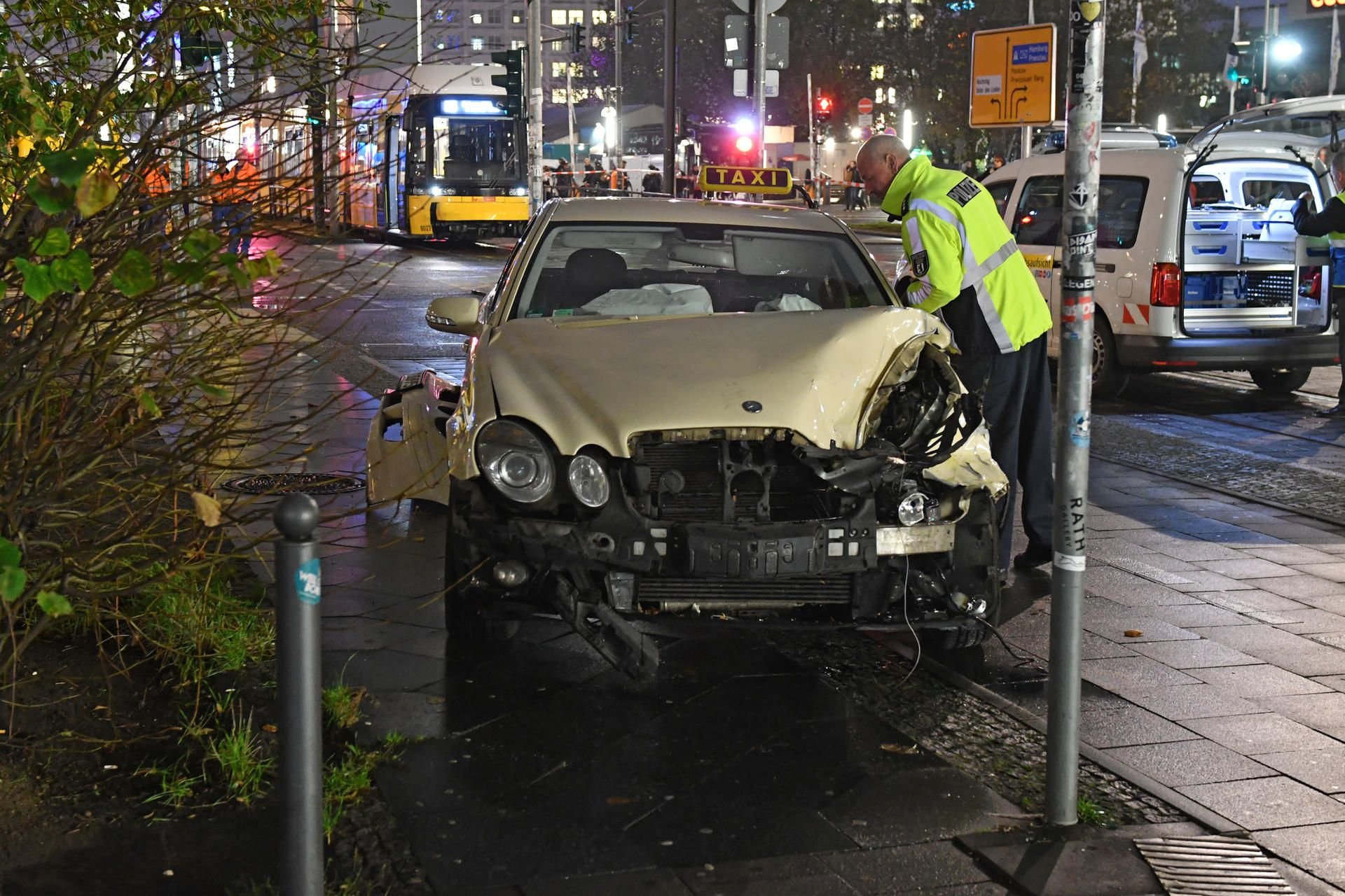 Ein nach einem Zusammenstoß mit einer Straßenbahn (hinten) demoliertes Taxi steht in Berlin am Alexanderplatz.