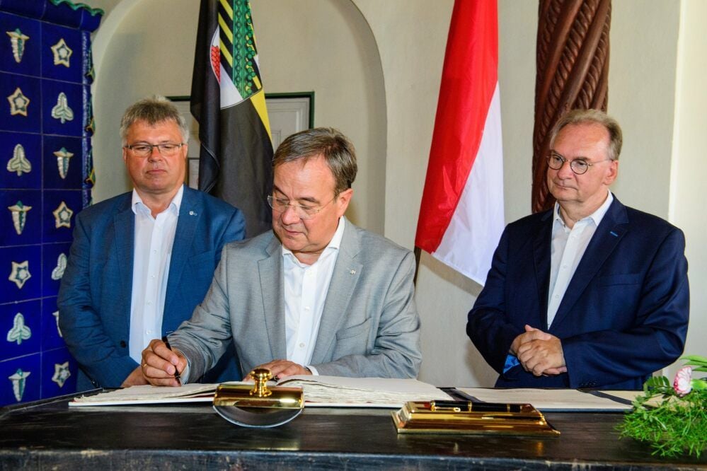 Armin Laschet trägt sich im Beisein von Ministerpräsident Reiner Haseloff (r.) und Oberbürgermeister Bernward Küper (l.) in das Goldene Buch der Stadt ein.