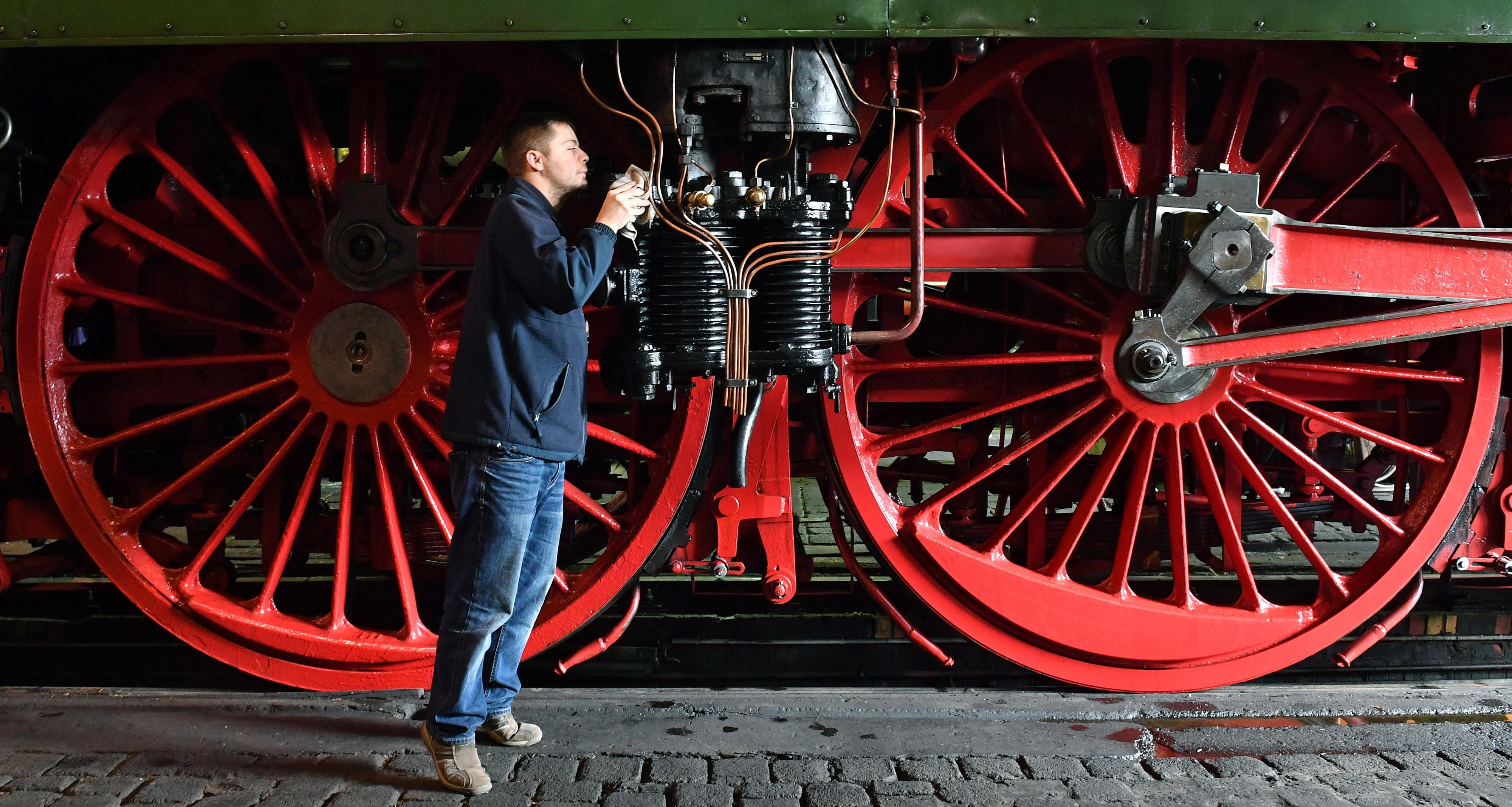 Vor den kapitalen Rädern der schnellsten betriebsfähigen Dampflok der Welt (18 201) arbeitet der ehrenamtliche Mitarbeiter Stefan Sawatzki im Lokschuppen des Eisenbahnmuseums