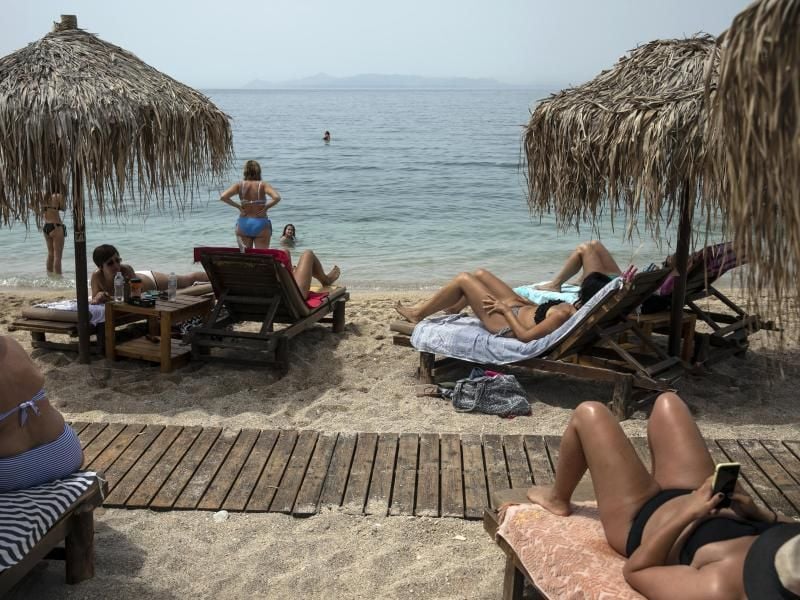 Urlauber liegen am Strand von Alimos (Griechenland). Foto: Yorgos Karahalis/AP/dpa