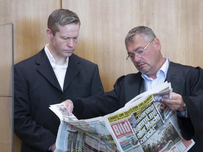 Stephan Ernst (l) mit seinem damaligen Verteidiger Frank Hannig, der in der Bild-Zeitung blättert. Foto: Boris Roessler/dpa/Archivbild