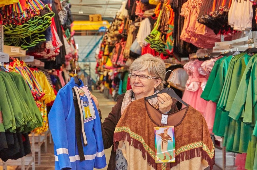 Betriebsleiterin Beate Cott zeigt in der großen Lagerhalle zwei Klassiker unter den Faschingskostümen: Feuerwehrmann und Indianerin.