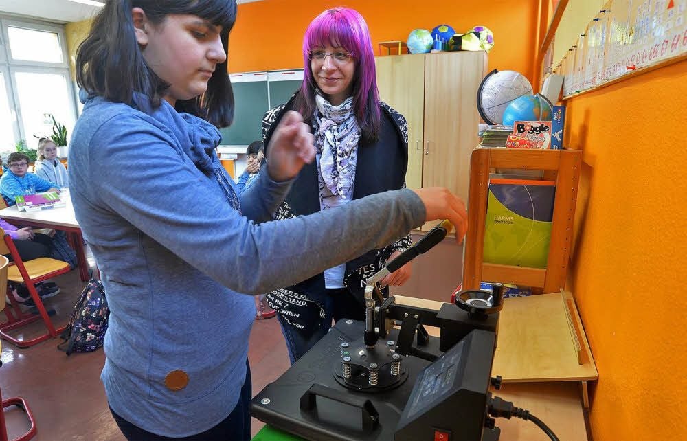 Unter Anleitung von Kerstin Hammer (r.) bedruckt Schülerin Jasmin Kahl ein T-Shirt für die Schülerfirma „Traumfabrik“.