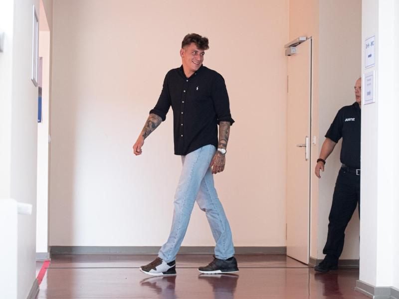 Rapper Gzuz (bürgerlich Kristoffer Jonas Klauß, l) geht über einen Gang vor dem Gerichtssaal. Foto: Daniel Reinhardt/dpa