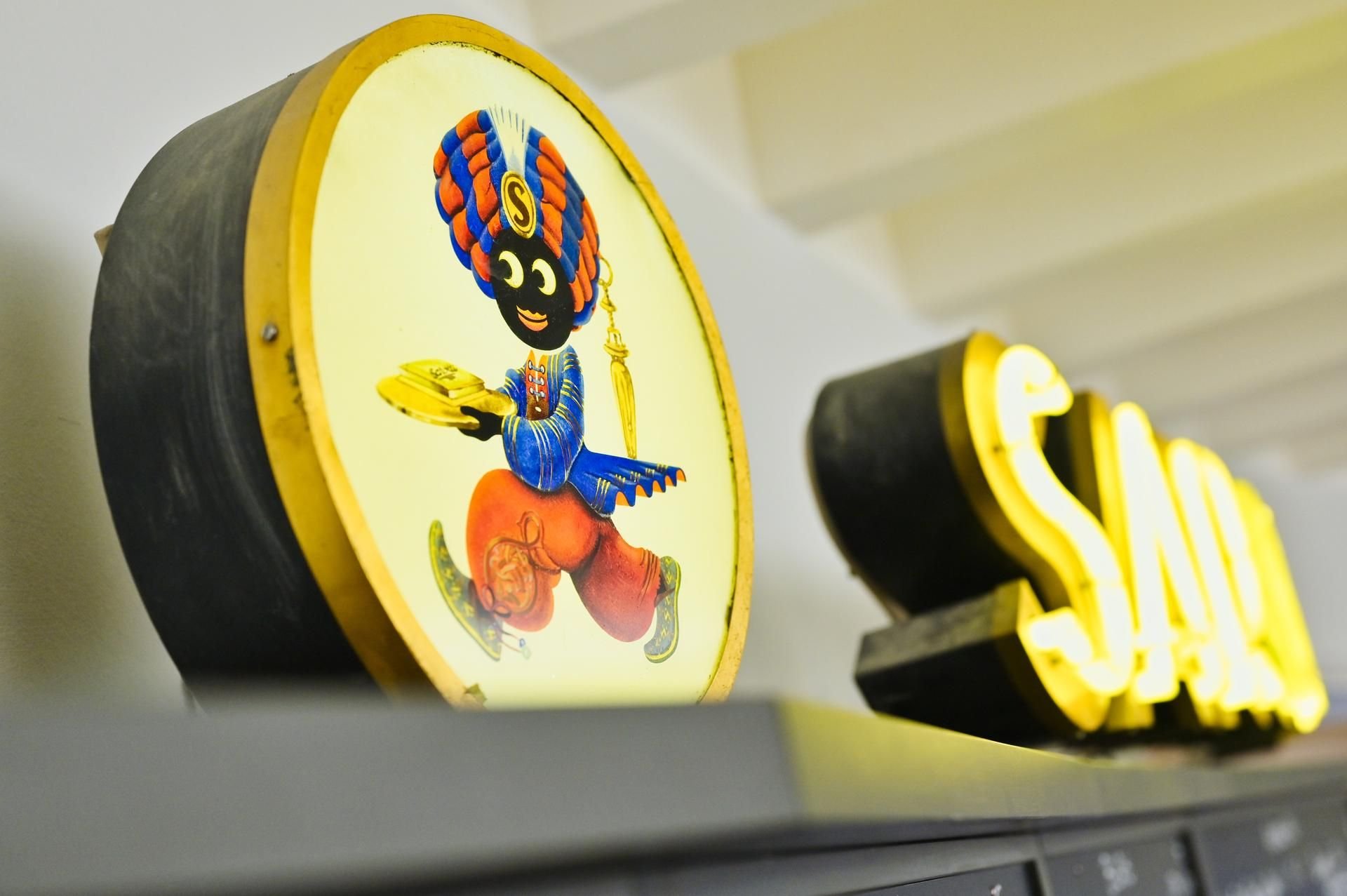 Ein beleuchtetes Werbeschild mit der Abbildung eines sogenannten „Sarotti-Mohr“ steht auf der Preistafel der Theke im Foyer des Mannheimer Kulturzentrums „Capitol“.