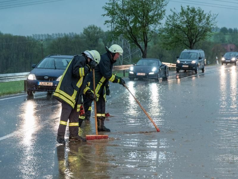 Feuerwehrleute versuchen die Wassermassen von der überschwemmten Bundesstraße B7 zwischen Weimar und Jena zu beseitigen. Foto: Johannes Krey