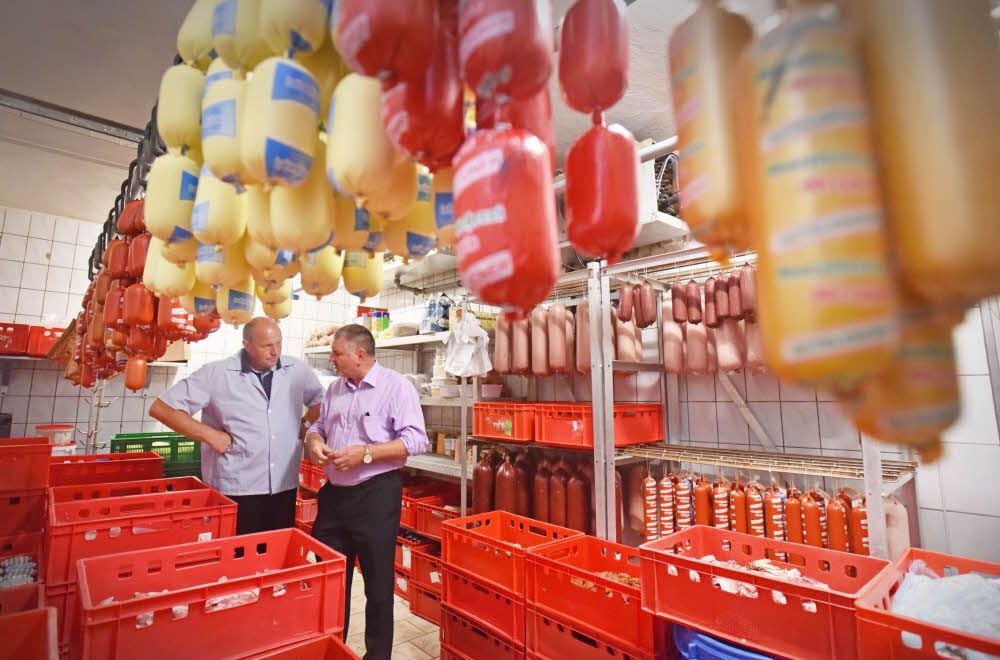Uwe Kuhlemann (l.) erklärt Landrat Uwe Schulze die Produktvielfalt seiner Gutsfleischerei in Greppin.