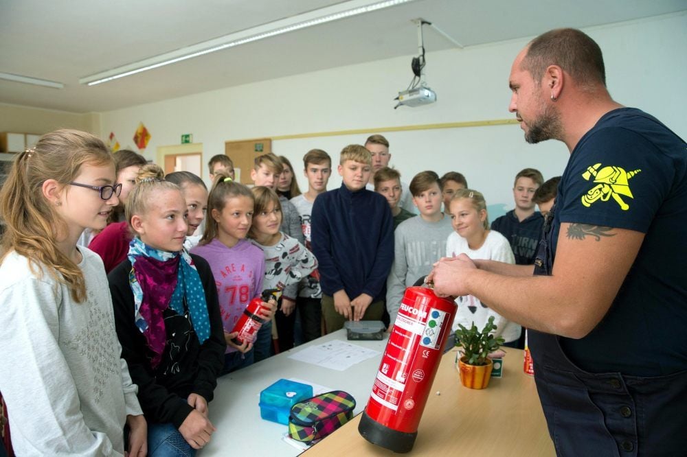 Torsten Boje von der Freiwilligen Feuerwehr Elster erläutert Sekundarschülern, welche Löscher sich gegen welche Brandarten eignen.