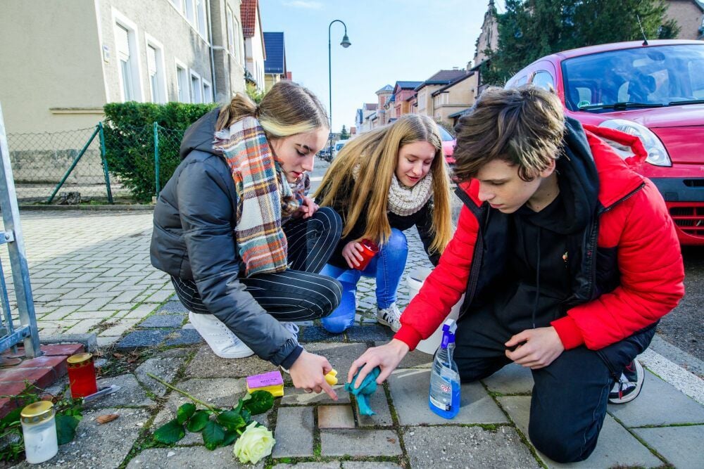 Die „Jan-Hus“-Schüler Cheyenne Schied, Jasmin Kranz und Lennart Zeitschel reinigen den „Stolperstein“ in der Naumburger Parkstraße in Gedenken an Dr. Arthur Samter, der vor seiner Deportation dort wohnte.