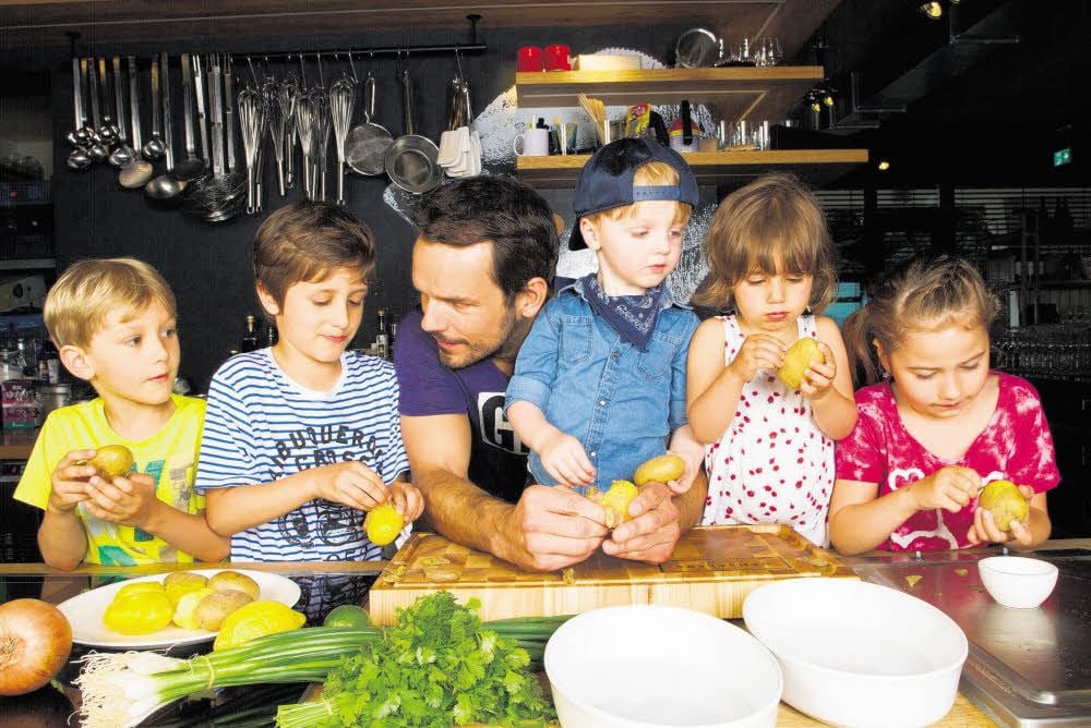 Hier bereitet Steffen Henssler mit Kindern Kartoffelsalat zu.