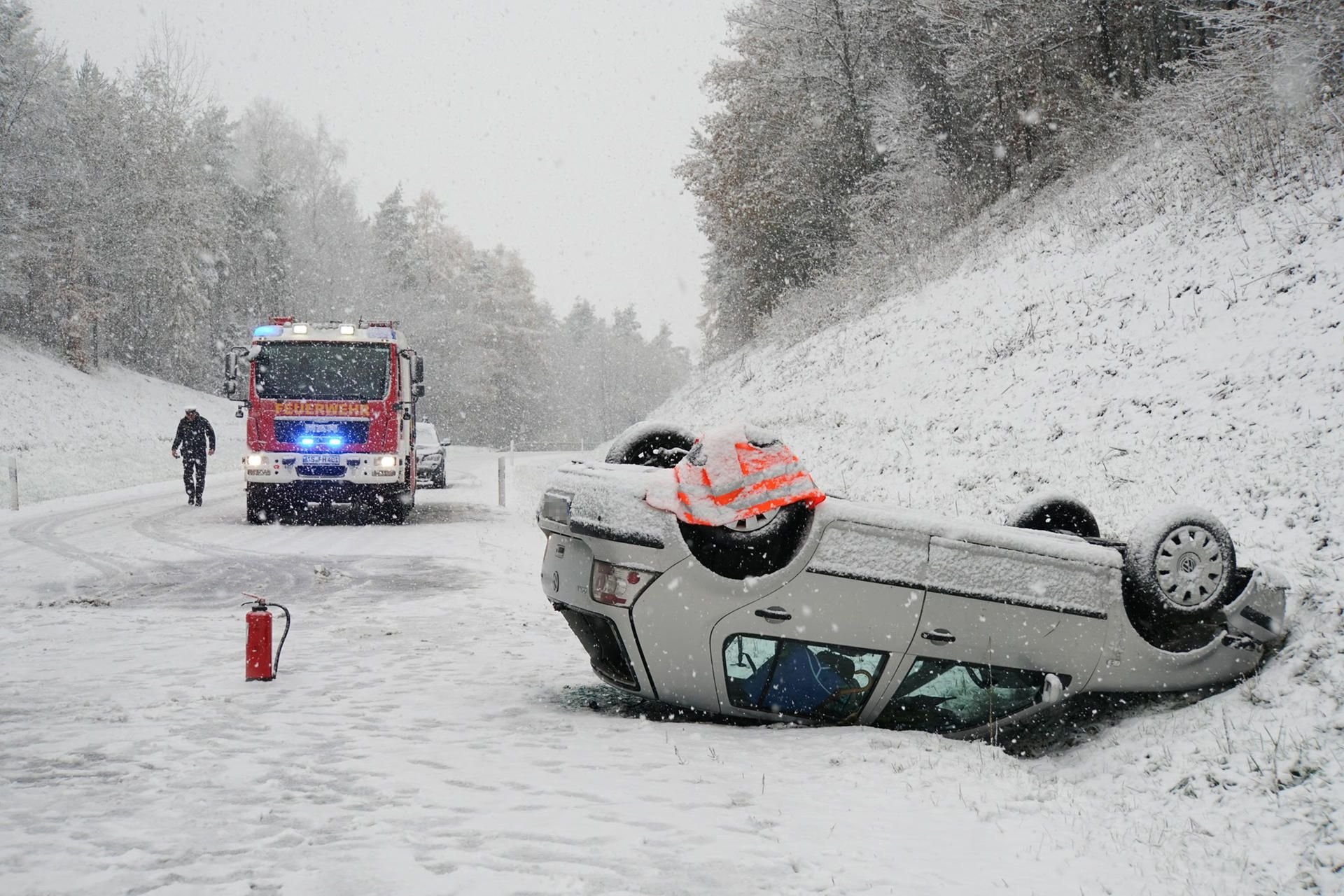 Ein Fahrzeug liegt nach einem Unfall auf schneebedeckter Fahrbahn auf der Bundesstraße 14 bei Hahnbach (Oberpfalz) auf dem Dach.