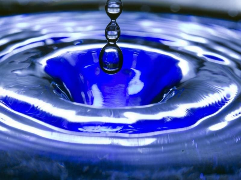 Ein Wassertropfen fällt in eine blaue Wasserschüssel. Foto: Jens Büttner/zb/dpa