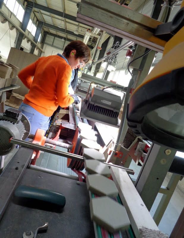 Aus dem Granulat, hergestellt aus Tonen, Feldspat und Farbstoff, werden die Industriefliesen gepresst, die im Foto oben vom Band laufen und von Ursula Schmidt verpackt werden.