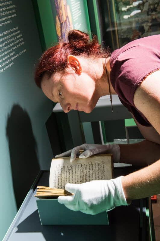 Museumsleiterin Andrea Knopik mit einem Band, der die Benediktinerregeln zweisprachig umfasst. Das Exponat aus dem 8. Jahrhundert stammt aus dem Bestand der Stiftsbibliothek in St. Gallen (Schweiz).