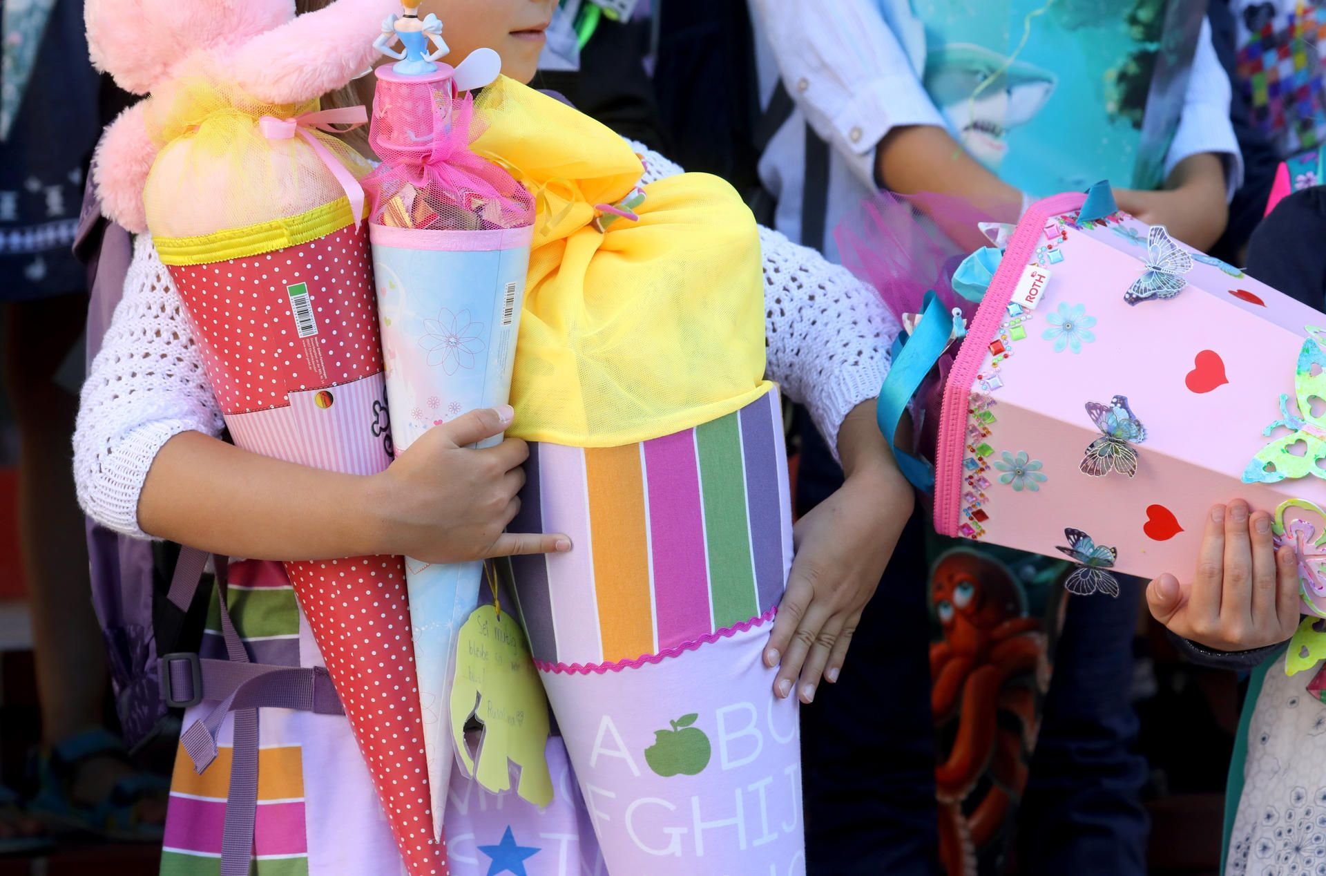 Kinder posieren nach ihrer feierlichen Einschulung mit Zuckertüten vor der Schule.