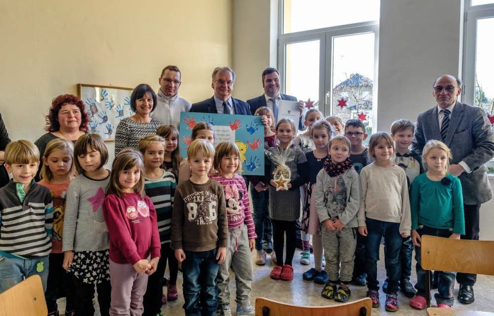 Ministerpräsident Reiner Haseloff übergibt den Fördermittelbescheid für die Möhlauer Kita und Hort an Bürgermeister Enrico Schilling im Beisein der Kinder.
