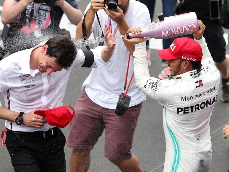 Lewis Hamilton (r) duscht Mercedes-Teamchef Toto Wolff mit Champagner. Foto: David Davies/PA Wire