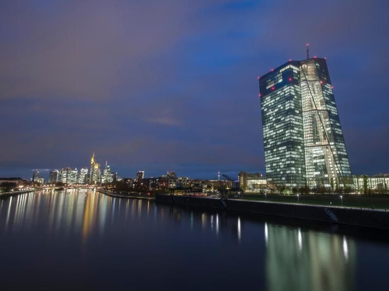 Die Lichter der Bürotürme leuchten hinter der Europäischen Zentralbank. Foto: Boris Roessler/Archiv