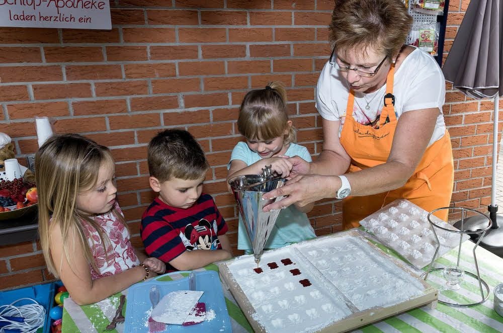 Charlotte, Tom und Ronja (v.l.) gießen mit Apotheken-Mitarbeiterin Liane Hoffmann Gummibärchen.