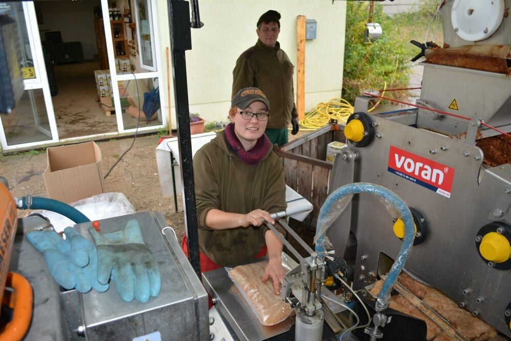 Während Elise Konschak an der mobilen Mosterei alles im Griff hat, platziert Obstbauer Sylvio Diethe die Saftbeutel in Kartons.
