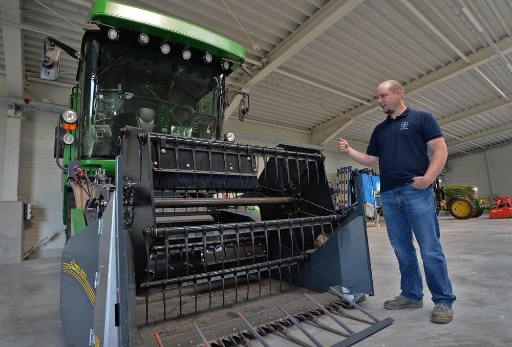 Farm-Manager Alexander Kirchherr zeigt den Parzellen-Mähdrescher, der in der neuen Halle untergebracht ist.