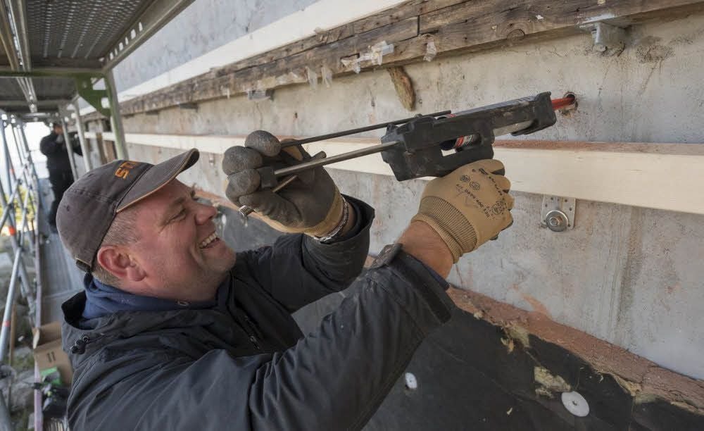 André Lorenz klebt Anker für die neue Fassade ein.