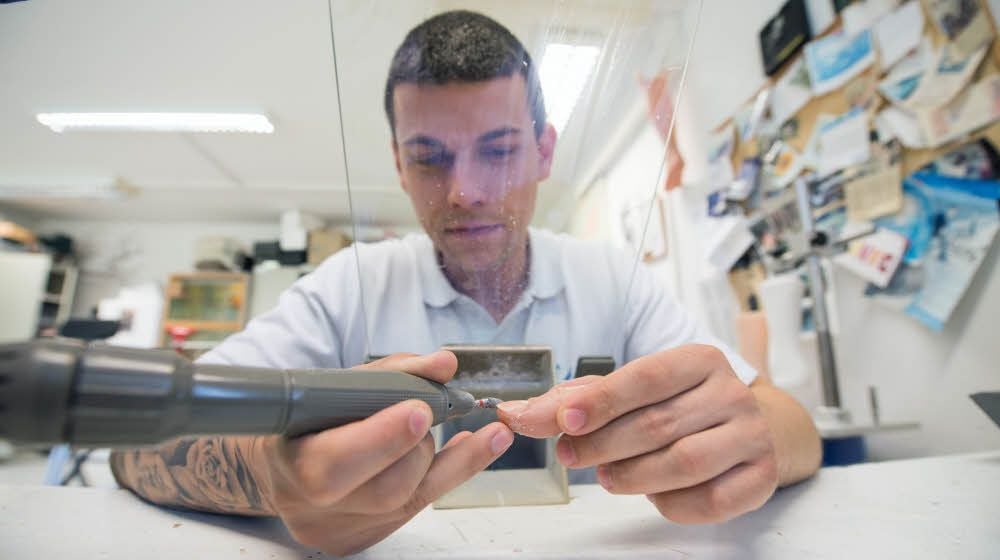 Orthopädietechniker Stefan Wandsleb fertigt eine Finger-Prothese: Er bringt den Fingernagel aus Acryl mit einer Feile in Form.