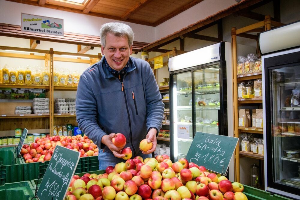 Im Agrarmarkt der Genossenschaft befüllt Vorstandsvorsitzender André Körner eine Kiste mit Äpfeln, die im Blütengrund gewachsen sind.
