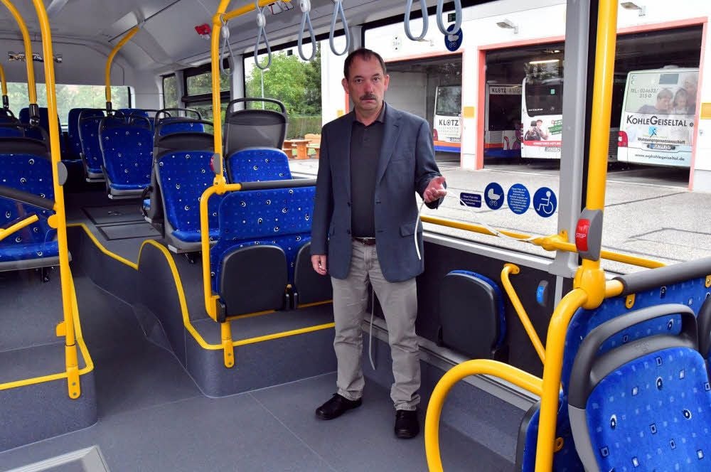 Lutz Däumler zeigt in einem Niederflurbus der PVG, wie Kinderwagen und Fahrräder gesichert werden können.