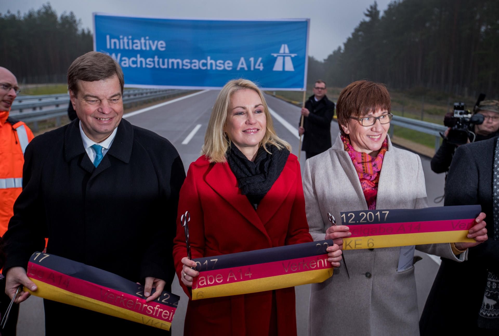 Die Ministerpräsidentin von Mecklenburg-Vorpommern, Manuela Schwesig (SPD, M), der Parlamentarische Staatssekretär im Bundesverkehrsministerium, Enak Ferlemann (CDU, l) und Brandenburgs Infrastrukturministerin Kathrin Schneider (SPD, r) zerschneiden in der Nähe von Grabow bei der feierlichen Verkehrsfreigabe eines Teilstücks der Bundesautobahn A14 das Band in den Deutschlandfarben.