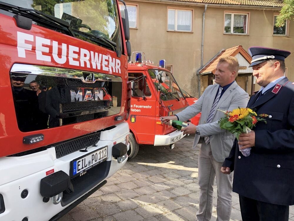 Eislebens Bürgermeister Carsten Staub (li.) bei der Sekttaufe des neuen Löschfahrzeuges der Polleber Feuerwehr