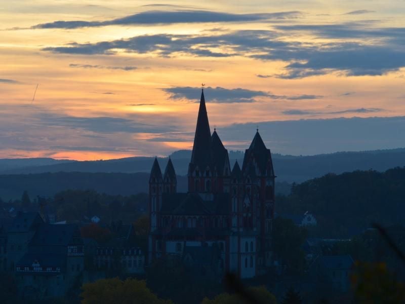 Die Sonne geht in Limburg hinter dem Dom der Stadt unter. Foto: Arne Dedert/Archiv