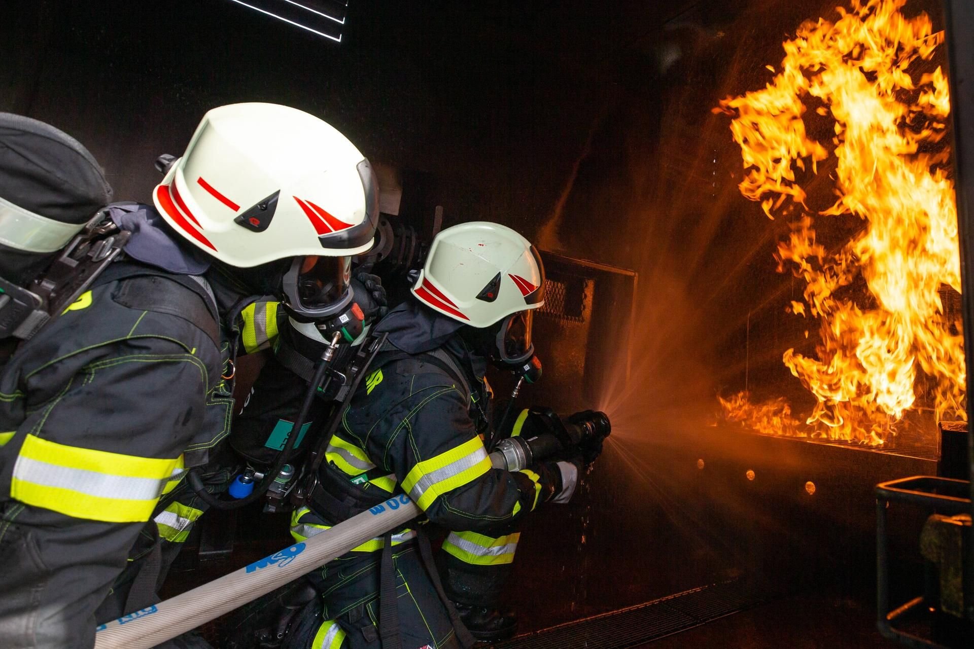 Zwei Feuerwehrkameraden kämpfen symbolisch mit einem Flash-Over im Brandübungscontainer.