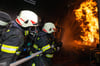 Zwei Feuerwehrkameraden kämpfen symbolisch mit einem Flash-Over im Brandübungscontainer.