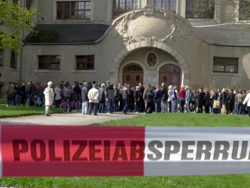 Ein Absperrband der Polizei trennt am 27.04.2002 vor dem Gutenberg-Gymnasium in Erfurt Medienvertreter von Trauernden. Foto: Stephanie Pilick/Archiv