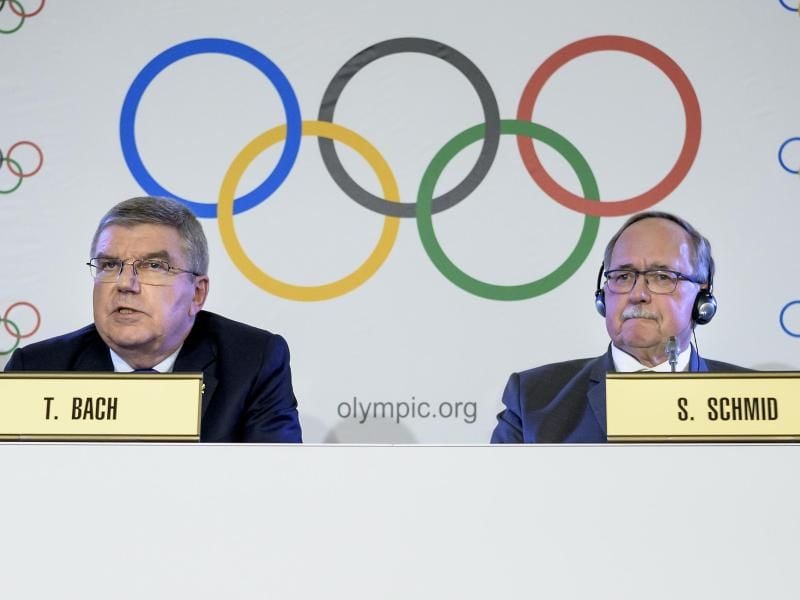 IOC-Präsident Thomas Bach (l) und der frühere Schweizer Bundespräsident Samuel Schmid teilen in Lausanne ihre Entscheidung mit. Foto: Jean-Christophe Bott