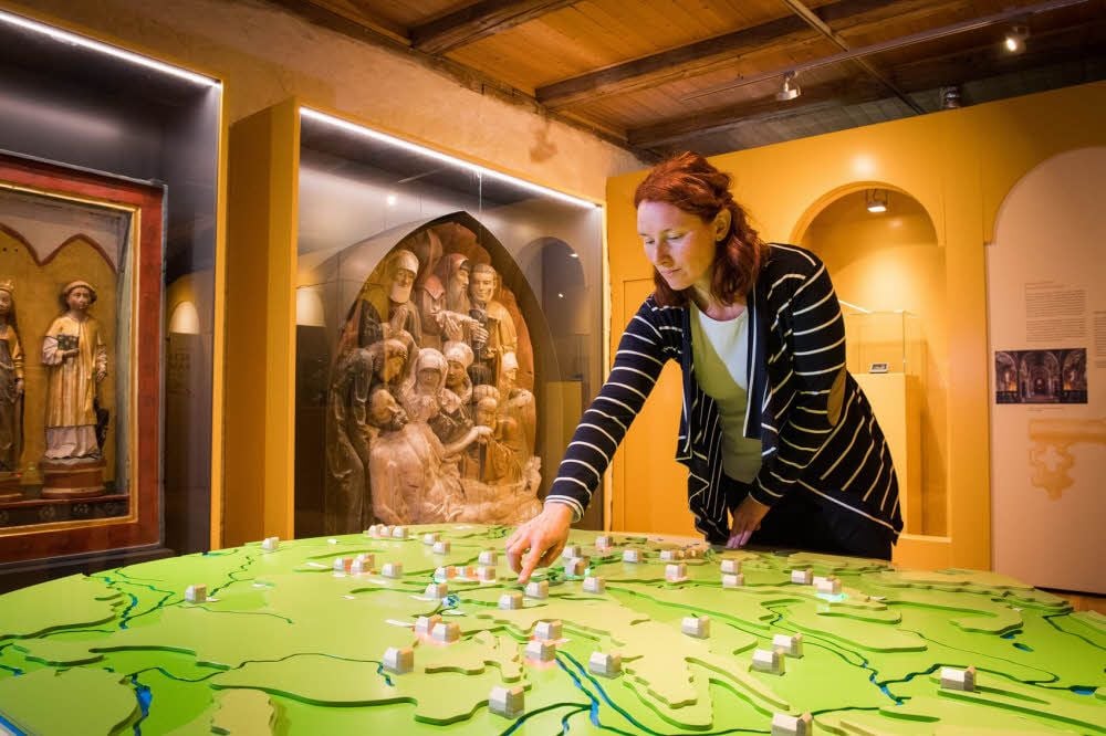 Museumsleiterin Andrea Knopik widmet sich dem Modell der hiesigen Klosterlandschaft. Im Hintergrund: ein Beweinungsrelief.
