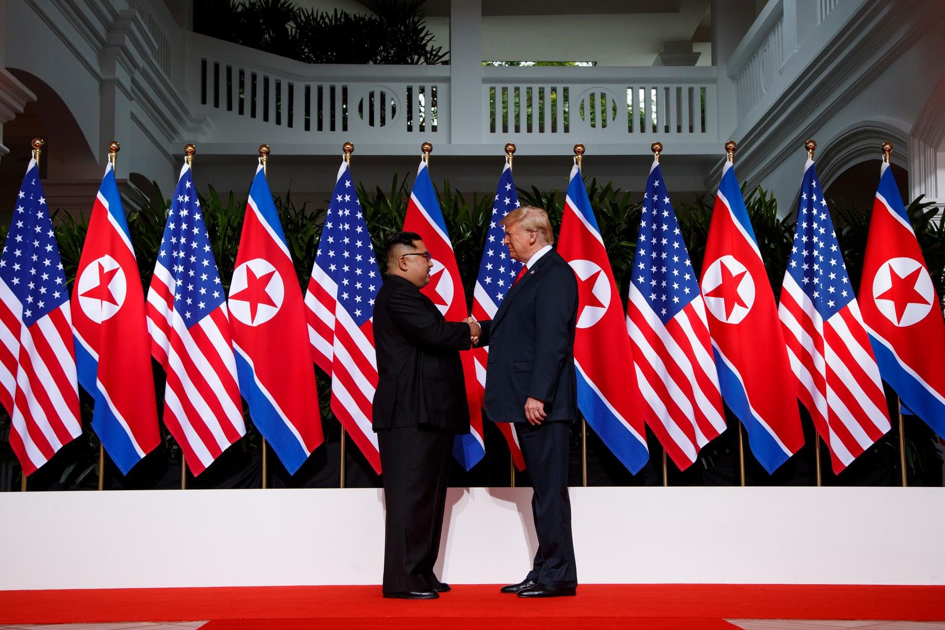 Donald Trump und Kim Jong Un schütteln sich die Hände.