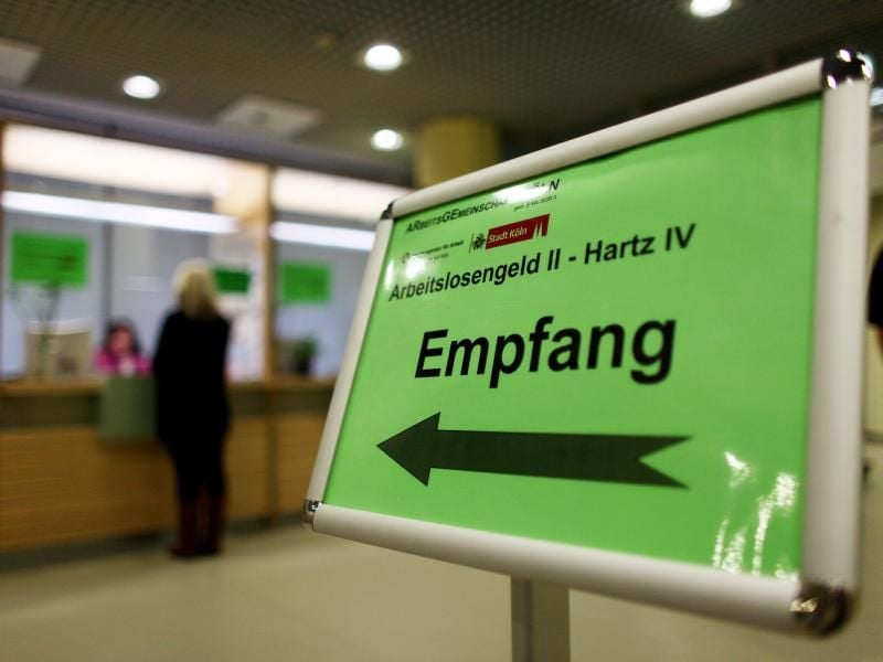 Eine Frau steht in der Arbeitsagentur am Empfangsschalter, um sich über die Beantragung von Hartz IV bzw. Arbeitslosengeld II zu informieren. Foto: Oliver Berg/Illustration