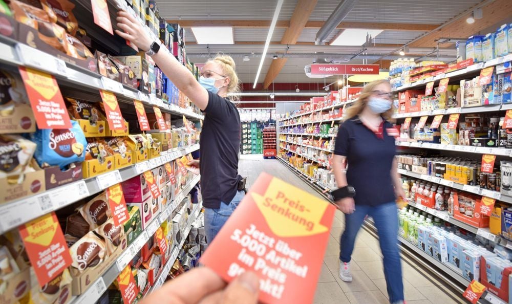 Eine Mitarbeiterin bringt im Bitterfelder Rewe-Supermarkt Preissenkungsschilder an.