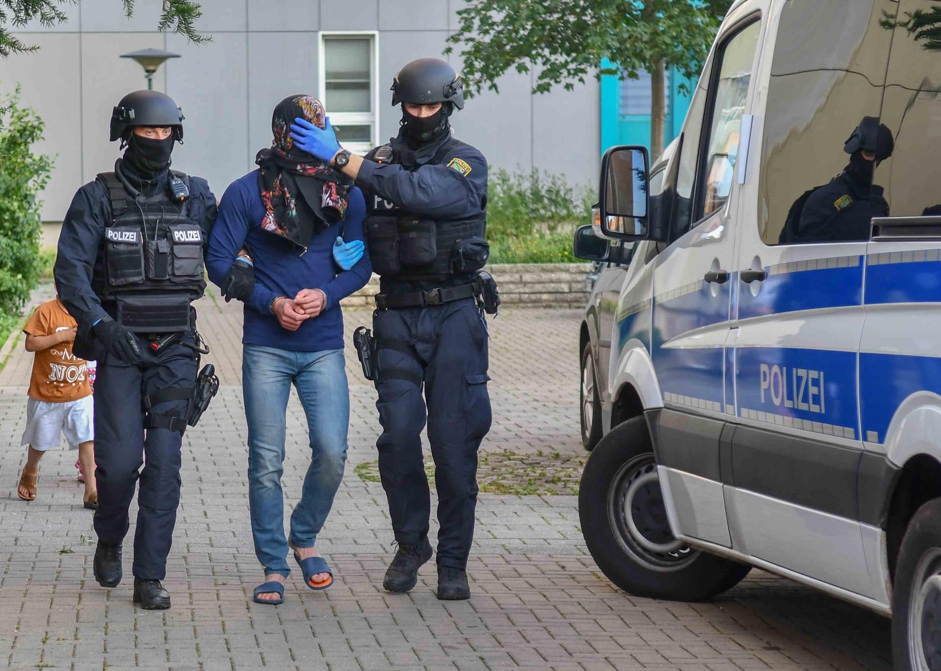 Bewaffnete Polizisten führen während einer Drogenrazzia einen Mann ab. Insgesamt wurden vier Männer im Alter zwischen 19 und 35 Jahren festgenommen.