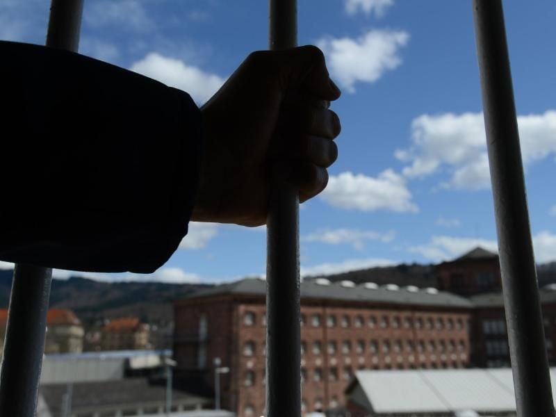 Ein Mann steht in der Justizvollzugsanstalt vor einem vergitterten Fenster. Foto: Patrick Seeger/Archiv