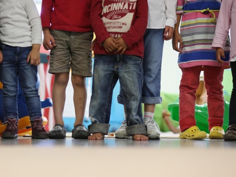 Kinder stehen in einem Kindergarten in einer Reihe. Foto: Christian Charisius/dpa/Archivbild