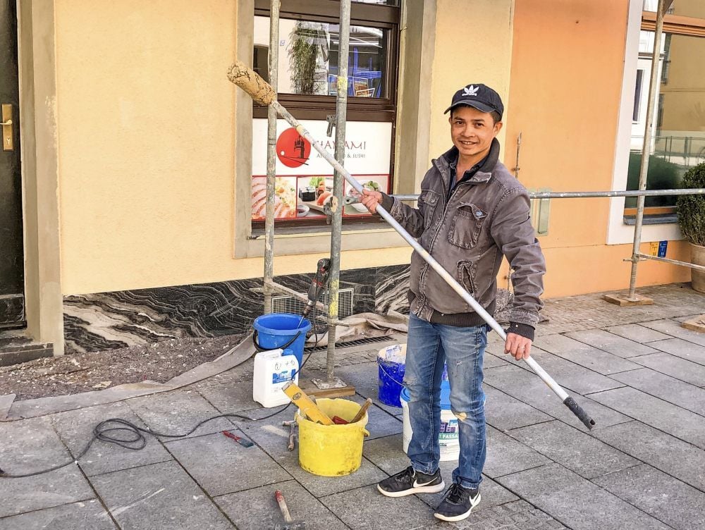 Phong Le beim Streichen der Fassade des Restaurants