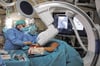Chefarzt Matthias Lenk mit seinem Team bei der Operation im Hybrid-Operationssaal. Im Vordergrund ist die Röntgeneinheit zu sehen.