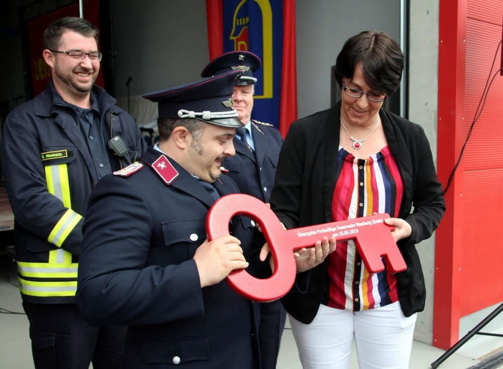 Ortswehrleiter Torsten Gerbeth nimmt den symbolischen Schlüssel zur neuen Feuerwache von Susan Falke entgegen. Dirk Niemann (links), Ortswehrleiter von Neugattersleben, und Stadtwehrleiter Rudi Waldeck freuen sich mit.