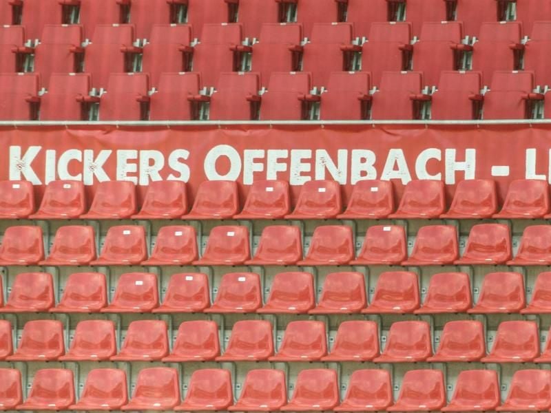 Leere Sitzreihen und ein „Kickers Offenbach” Schriftzug im Offenbacher Stadion. Foto: Boris Roessler/dpa/Archivbild